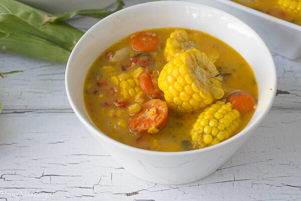 A white bowl with finished corn soup with corn, carrots and dumplings.