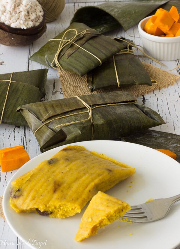 A bunch of paimes wrapped in banana leaf and on a white background with shredded coconut.