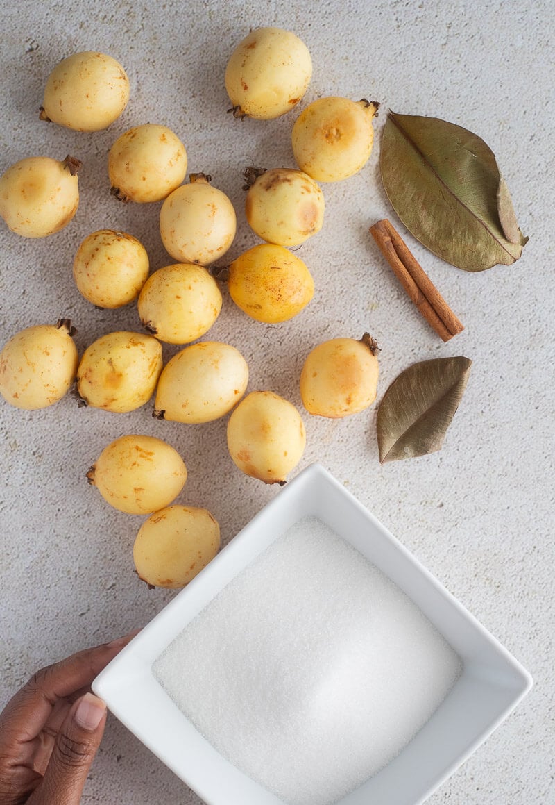 Guavas, bayleaf, cinnamon and sugar on top a white board.