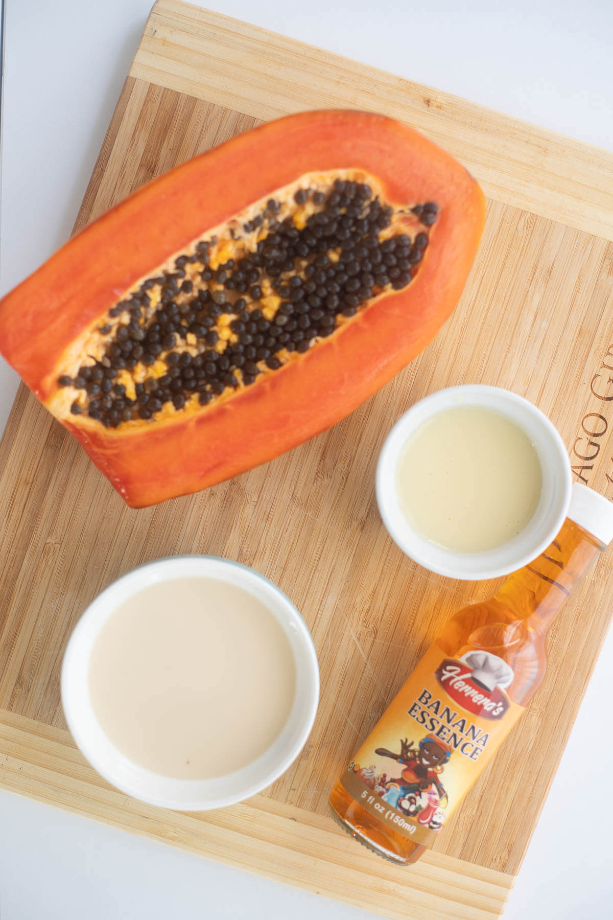 Ripe pawpaw with different milks on a wooden table for a pawpaw drink recipe.