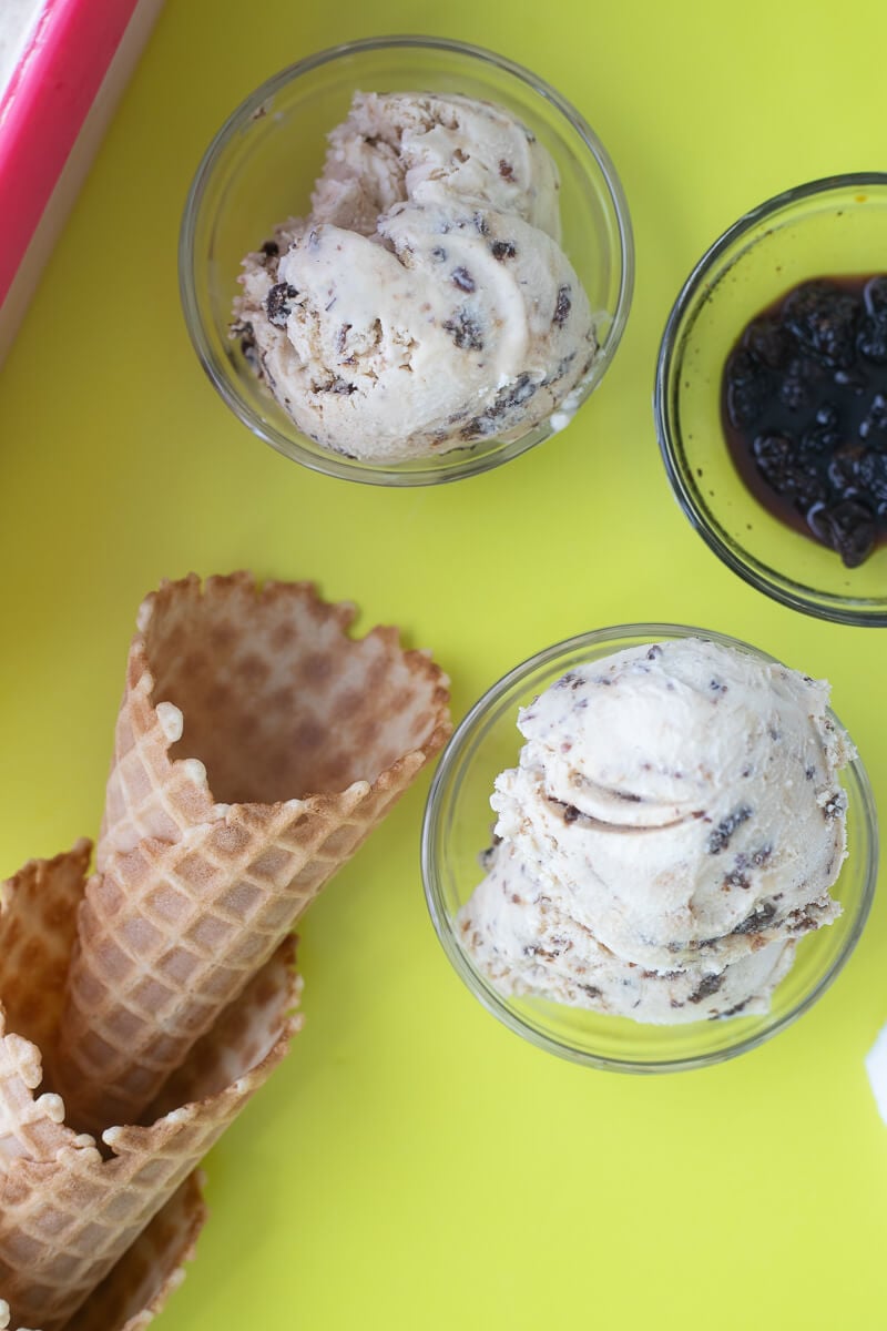 Scoops of ice cream in glass bowls with ice cream cones on the side.