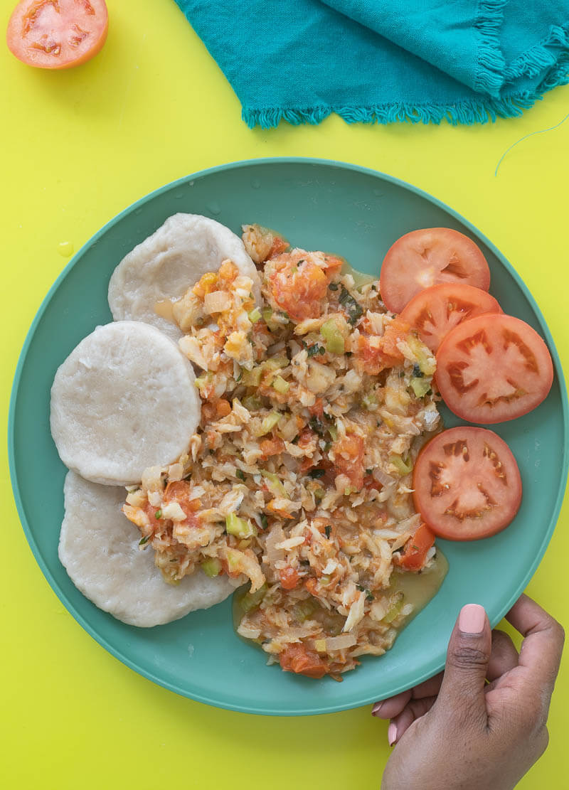 A plate of boiled dumplings paired with some stewed saltfish.