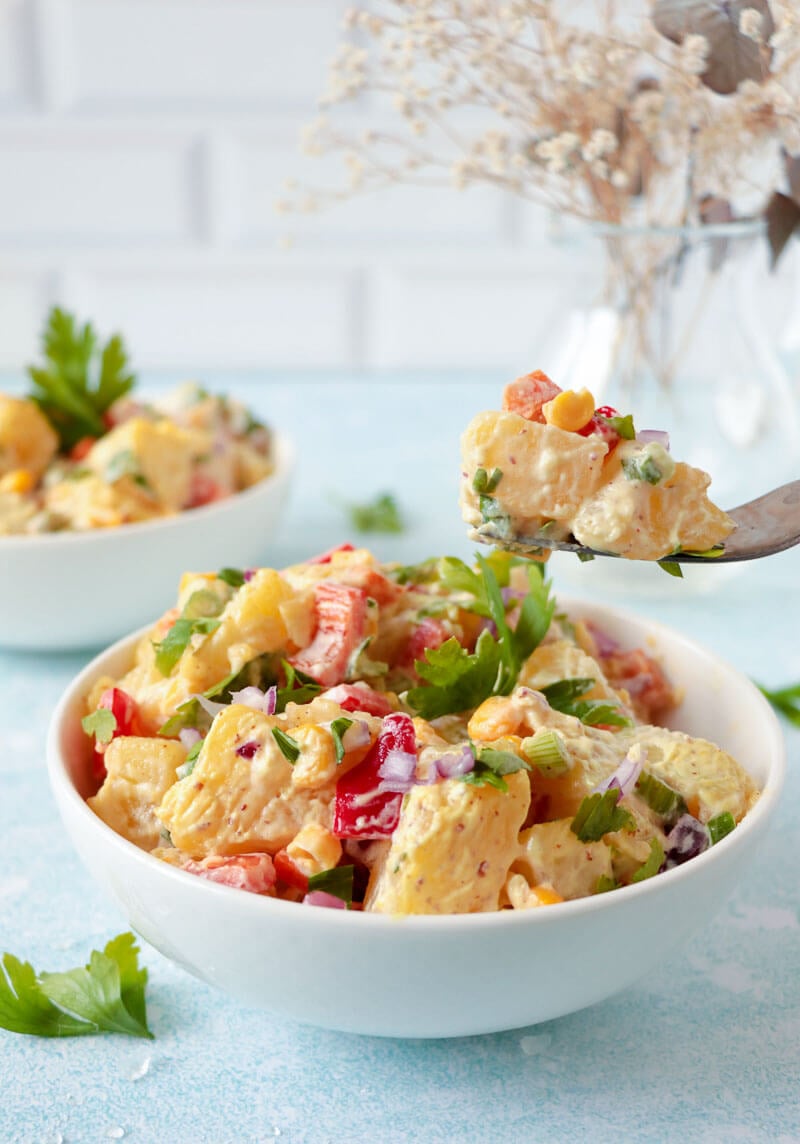 A forkful of salad lifted over a full serving.