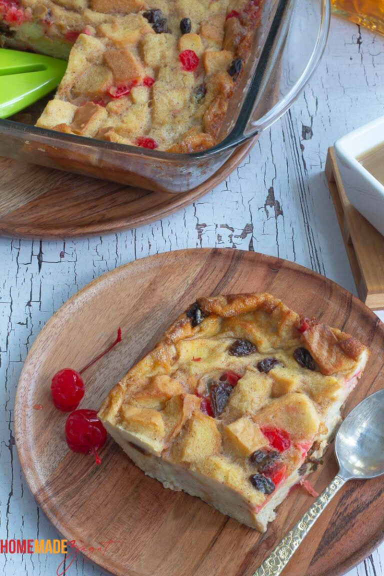 A slice of bread pudding on a wooden plate with a white background