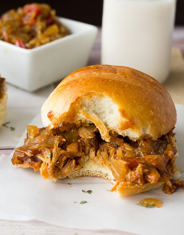 A chicken sandwich with a bite on it showing off the topping of pineapple chutney.