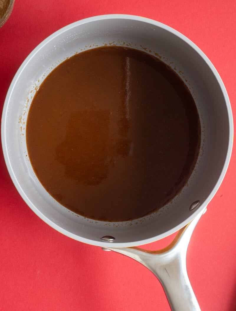 Jerk BBQ sauce in a pot on a red backdrop.