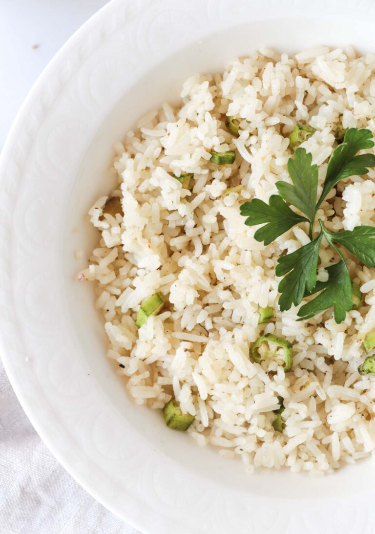 Close up of cooked ochro and rice in a white bowl.