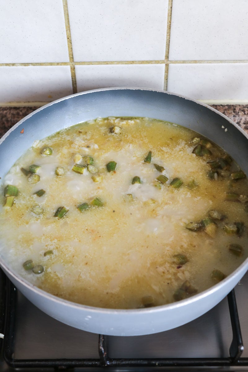 Water and coconut milk added to pot boiling with rice and seasonings.