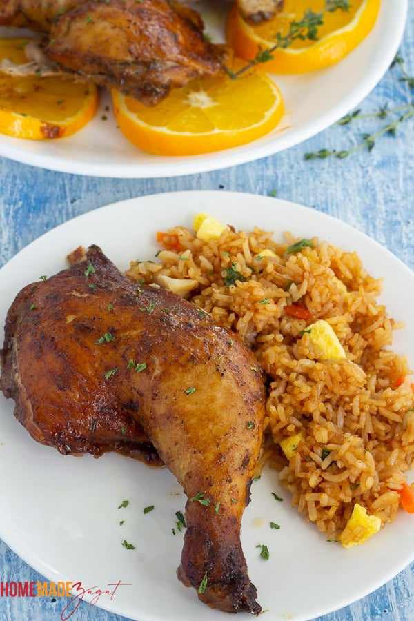 Orange ginger chicken leg quarter with fried rice on a white plate