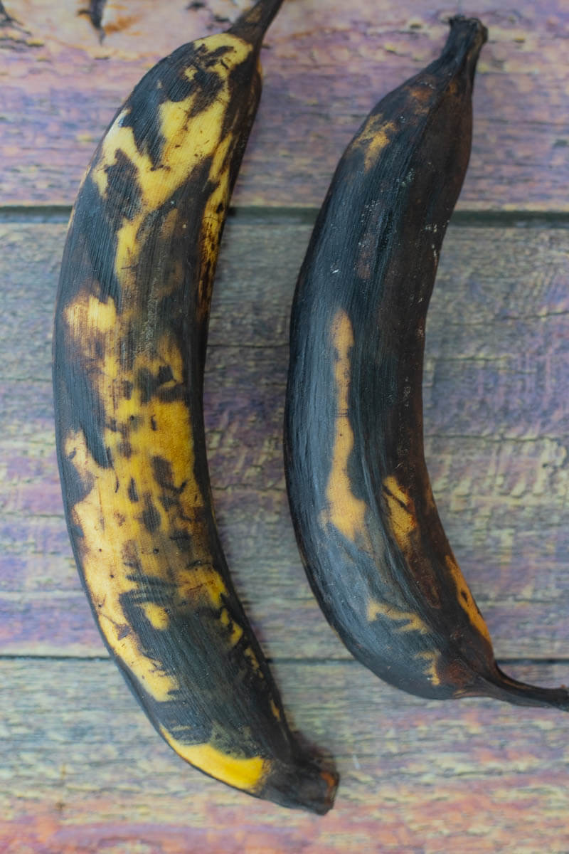 Two plantains that are very ripe that were chosen to be fried.