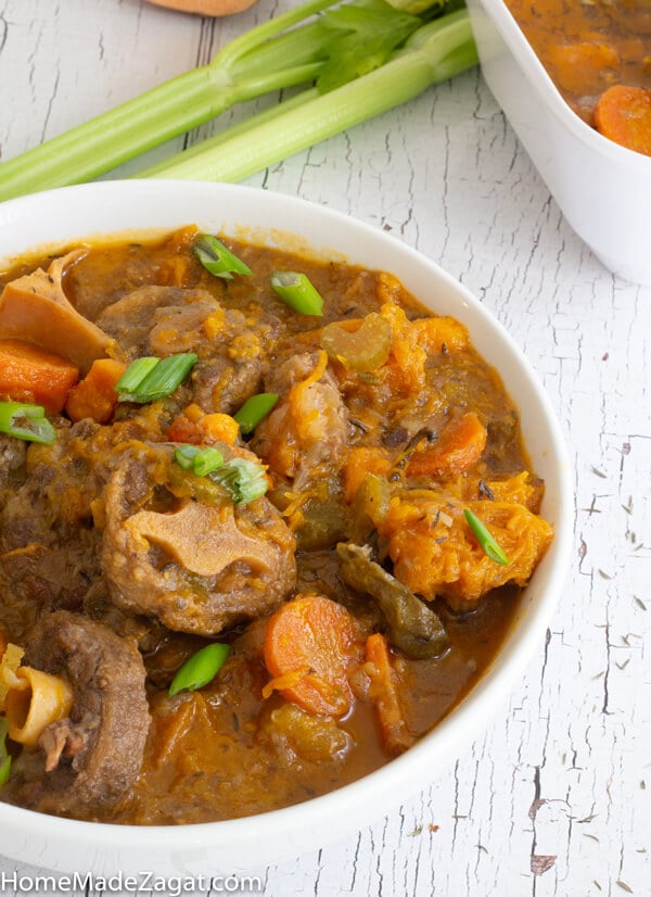 Serving of a bowl of oxtail soup on a white background.