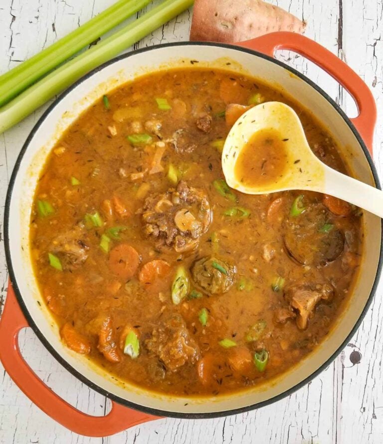 Pot of finished oxtail soup made in the slow cooker served in a wide dutch pot.