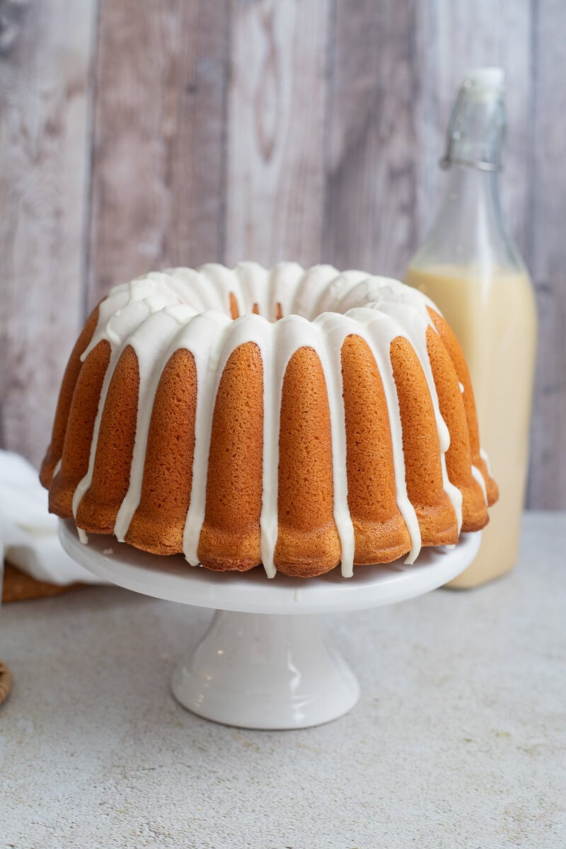 Ponche de creme pound cake with glaze on a white cake stand.