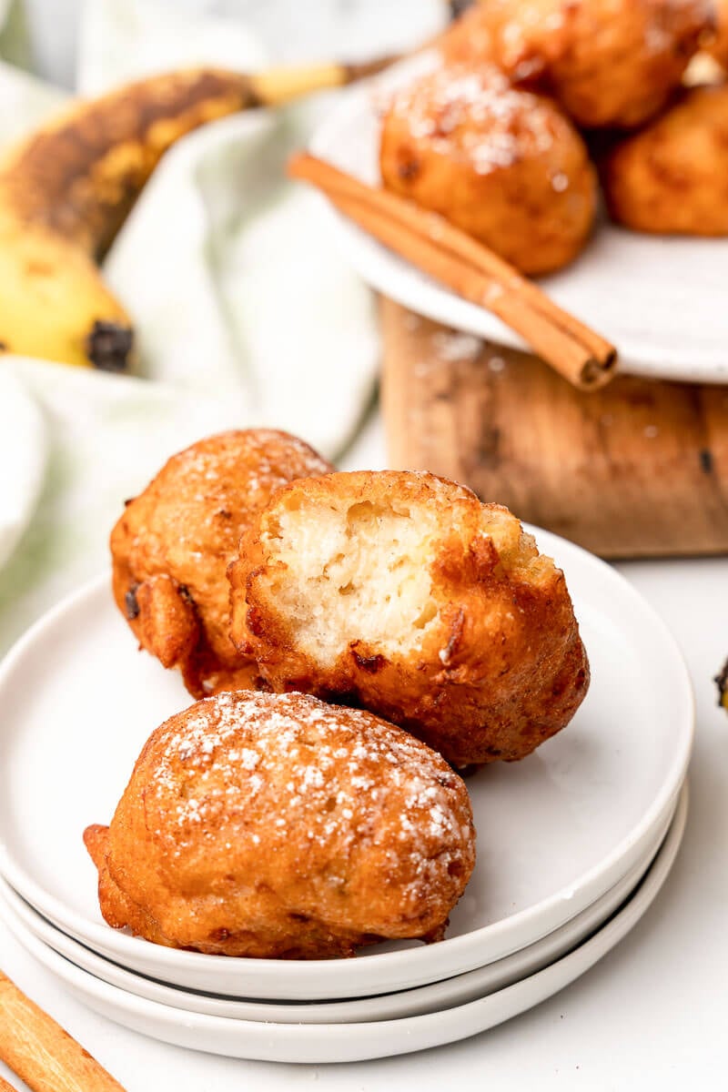 Fried banana fritters on a plate with a bite.