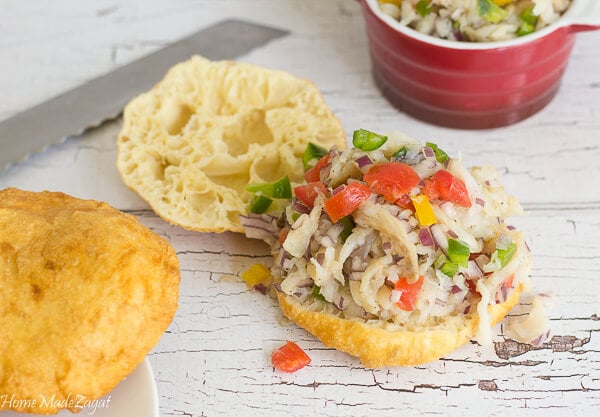 Two fried bakes topped with saltfish on a plate.