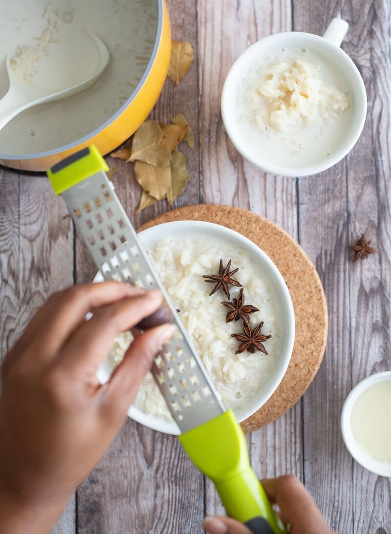 Grating of fresh nutmeg into a finished bowl of creamy rice porridge.