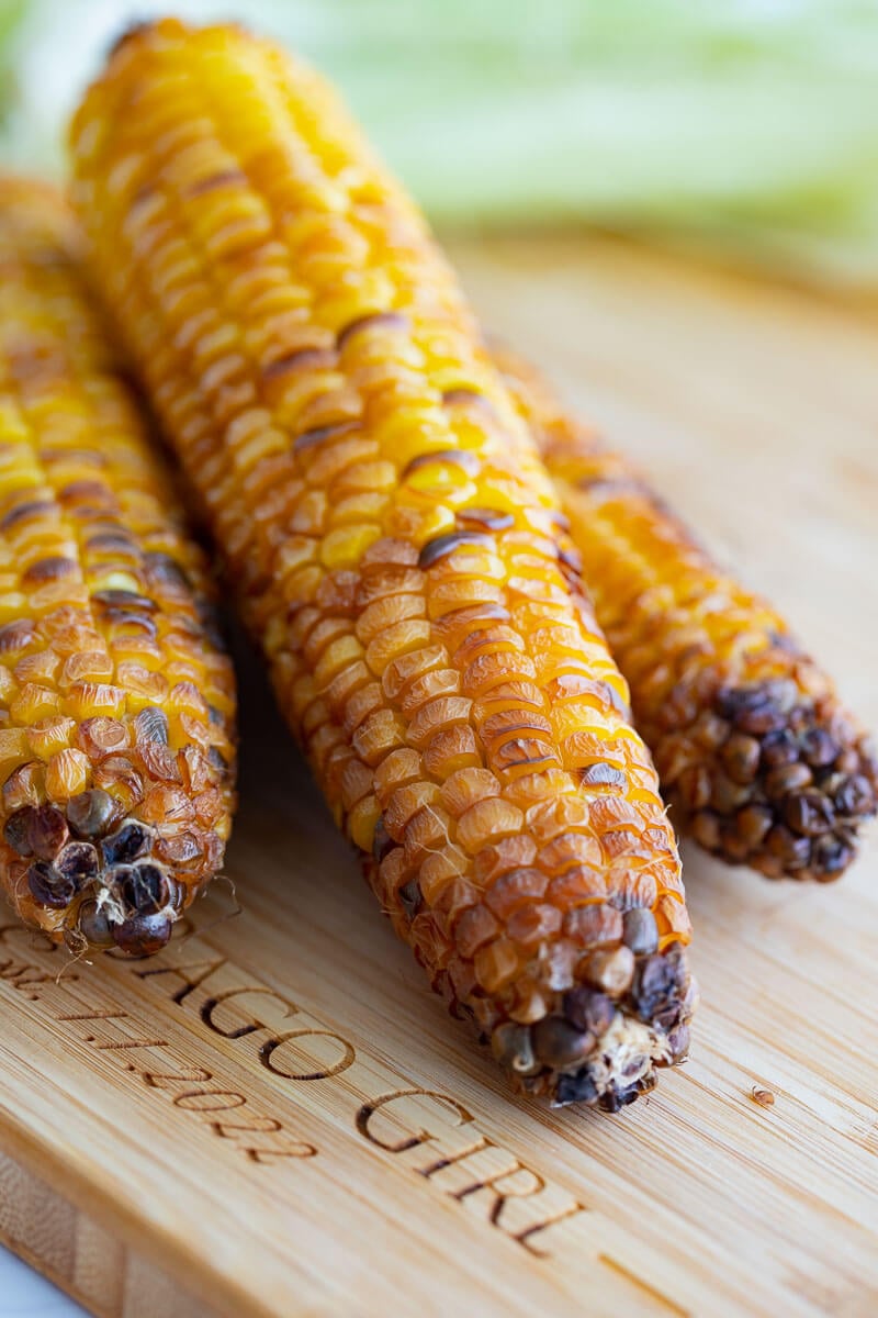 Close up of roasted corn ends on a wooden board.