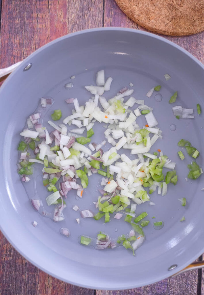 Scallions and shallots in coconut oil being sauteed.