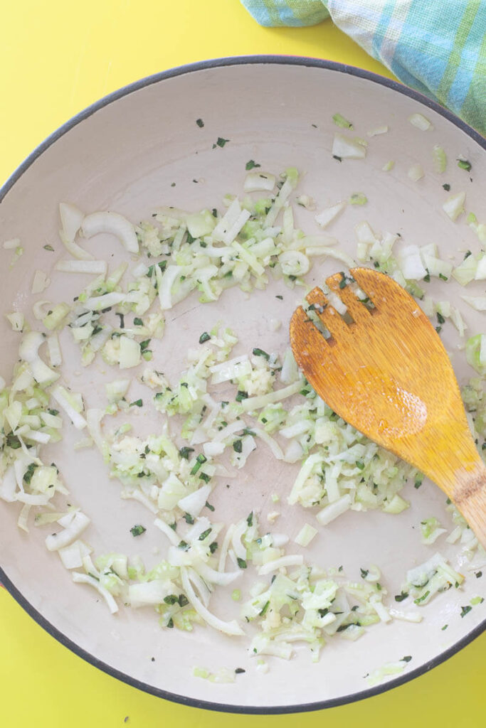 Sautéing of onion and garlic in vegetable oil in a cast iron pot.