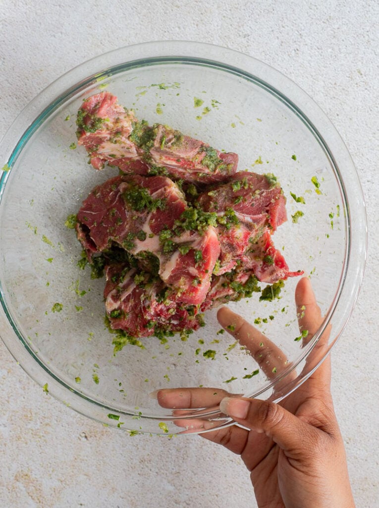 Seasoned beef neck with green seasoning and garlic in a clear bowl.