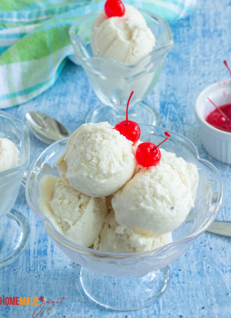Glasses of soursop ice cream topped with cherries, served on a blue checkered cloth.