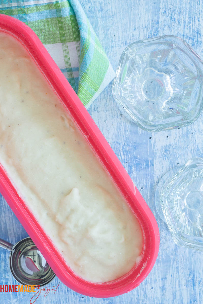 Soursop ice cream in a ice cream tub with a scoop and empty cups