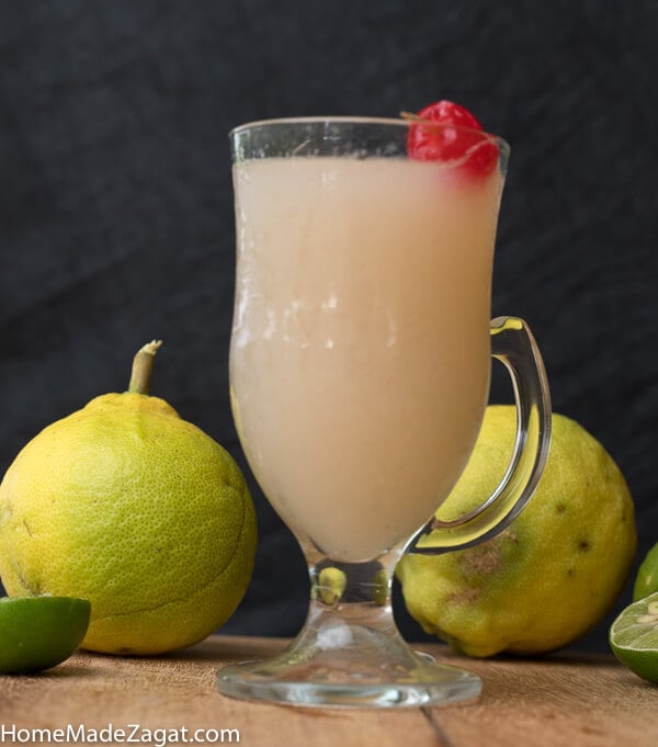 A glass of soursop drink with cherries on top.