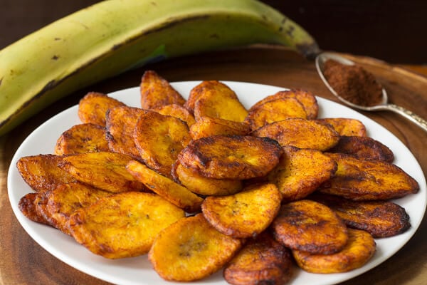 Finished spicy fried plantains, spread out on a white plate.