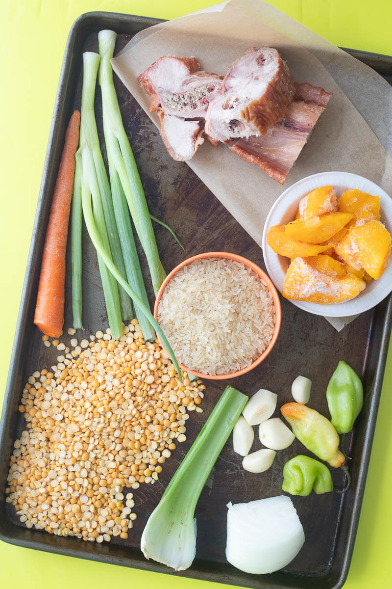 Ingredients for making split peas and rice cook-up on a baking tray on a green counter top.