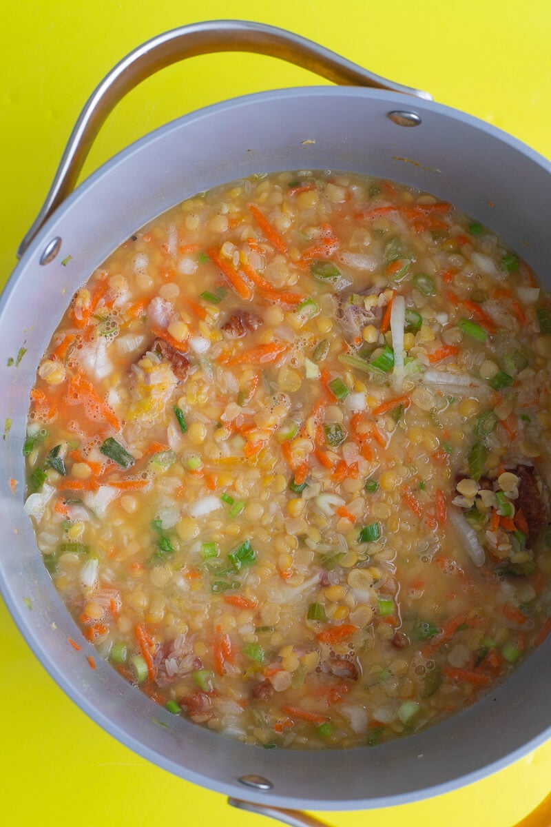 Split peas ingredients all in one pot ready to be steamed down on top of a yellow counter.