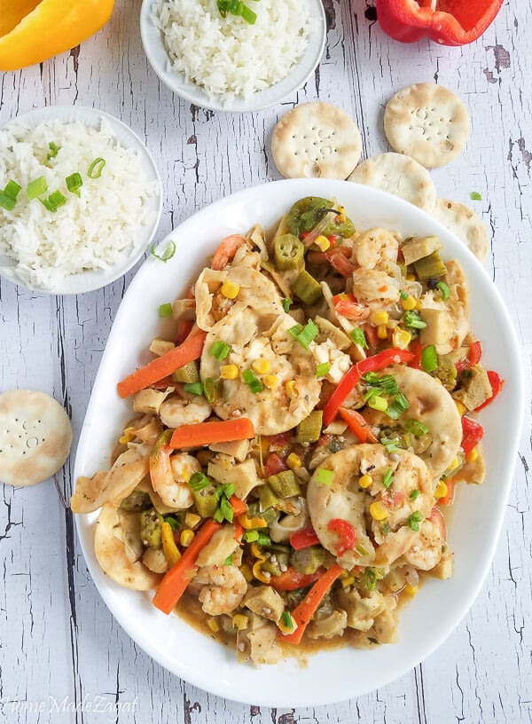 Steam conch with crackers and veggies in a white plate with rice on the side