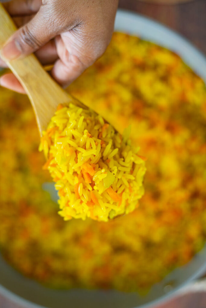 Steamed carrot rice, on a spoon, ready to be served.