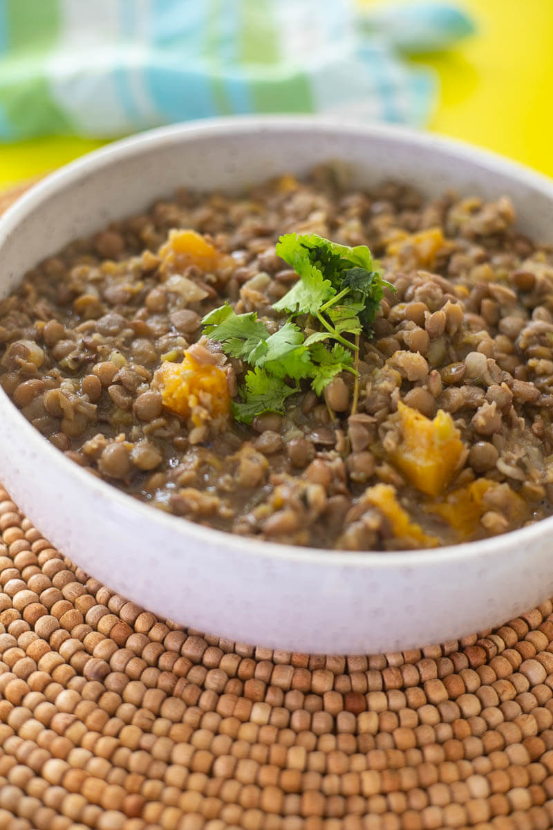 A white bowl full of low-simmered lentil peas with pumpkin.