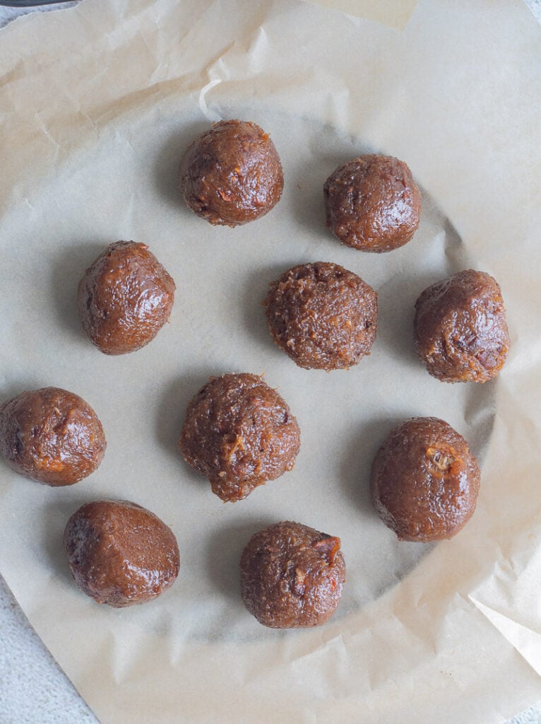 Shaped tamarind balls on wax paper on a textured back drop..