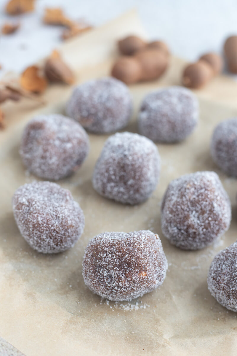 Close up of tamarind balls with sugar on a wax paper sheet.