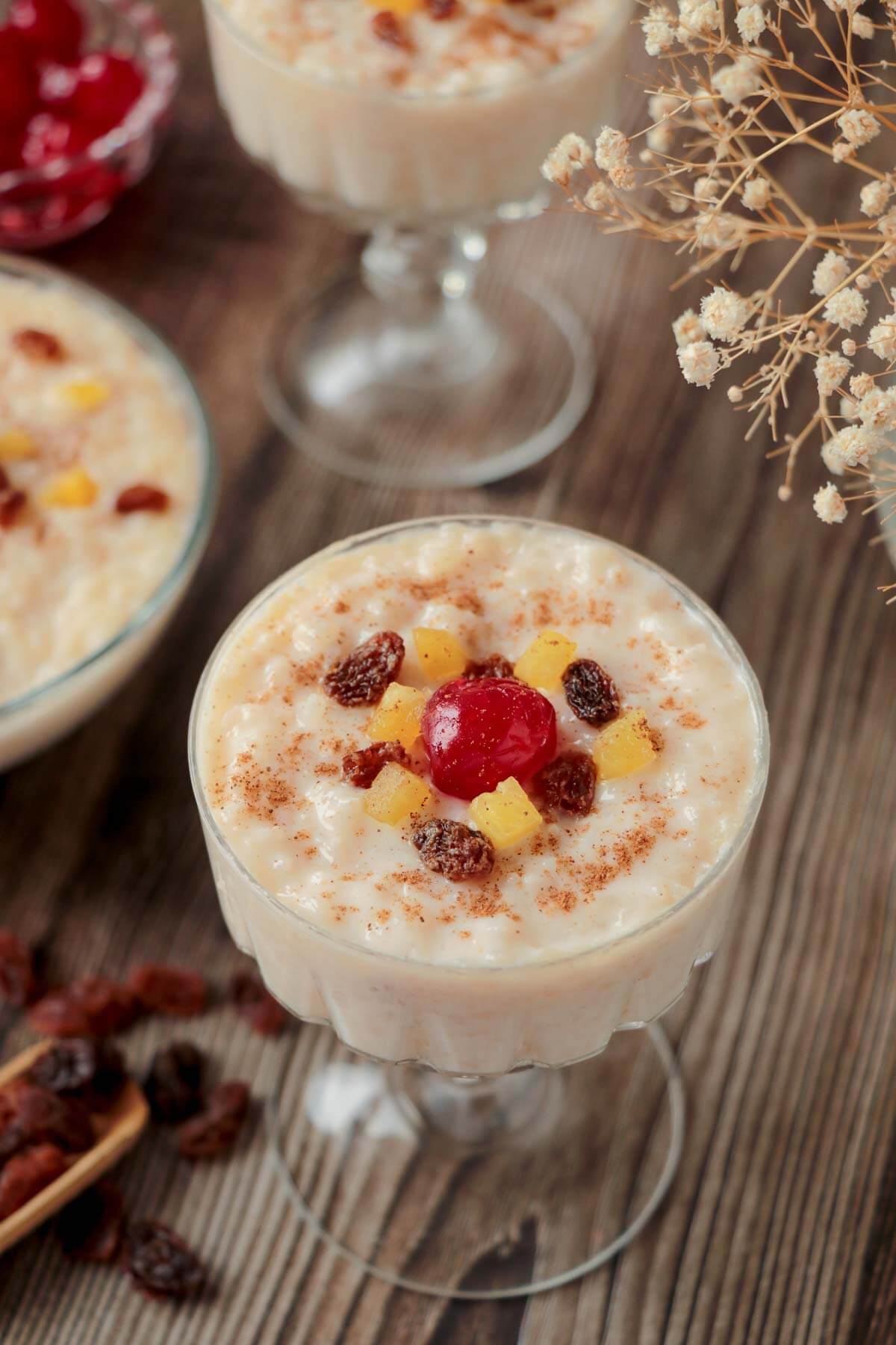 Two glasses of Trinidad sweet rice topped with fruits and a dusting of cinnamon powder.