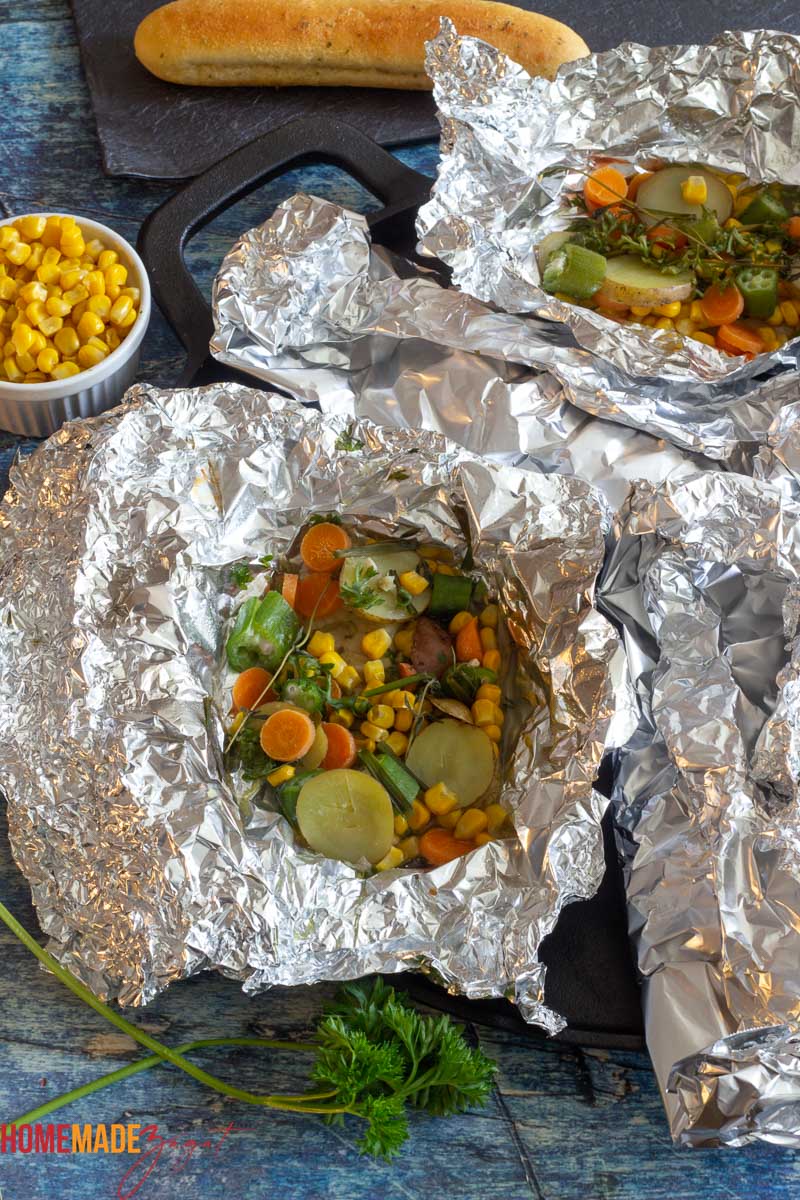 Opened packets of fish in foil with veggies