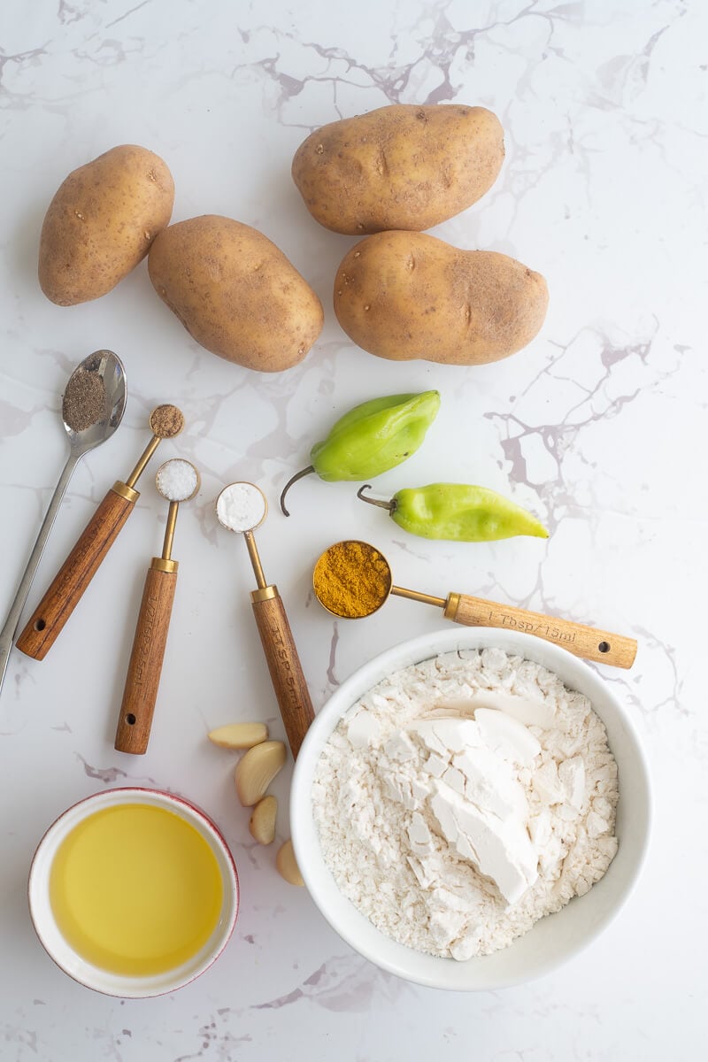 Ingredients for making Trini aloo pie portioned out and on a white background.