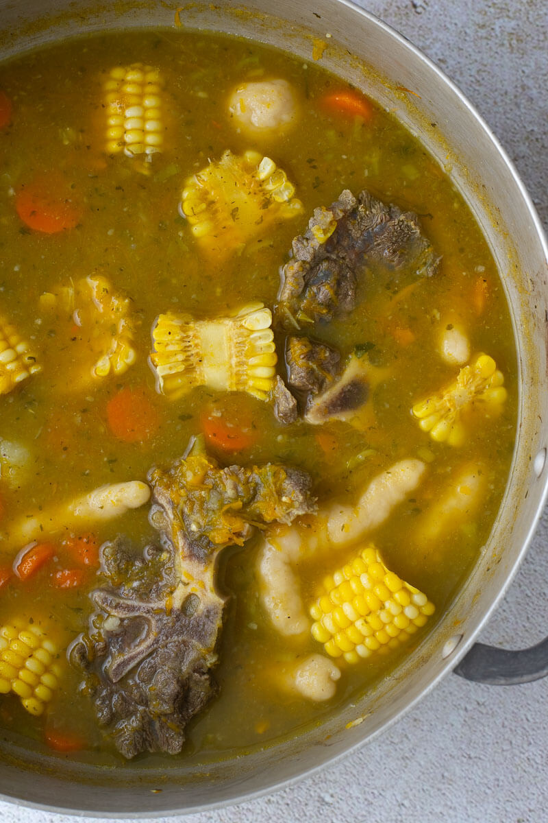 Soup finished and combined in a medium metal pot on a creme backdrop.