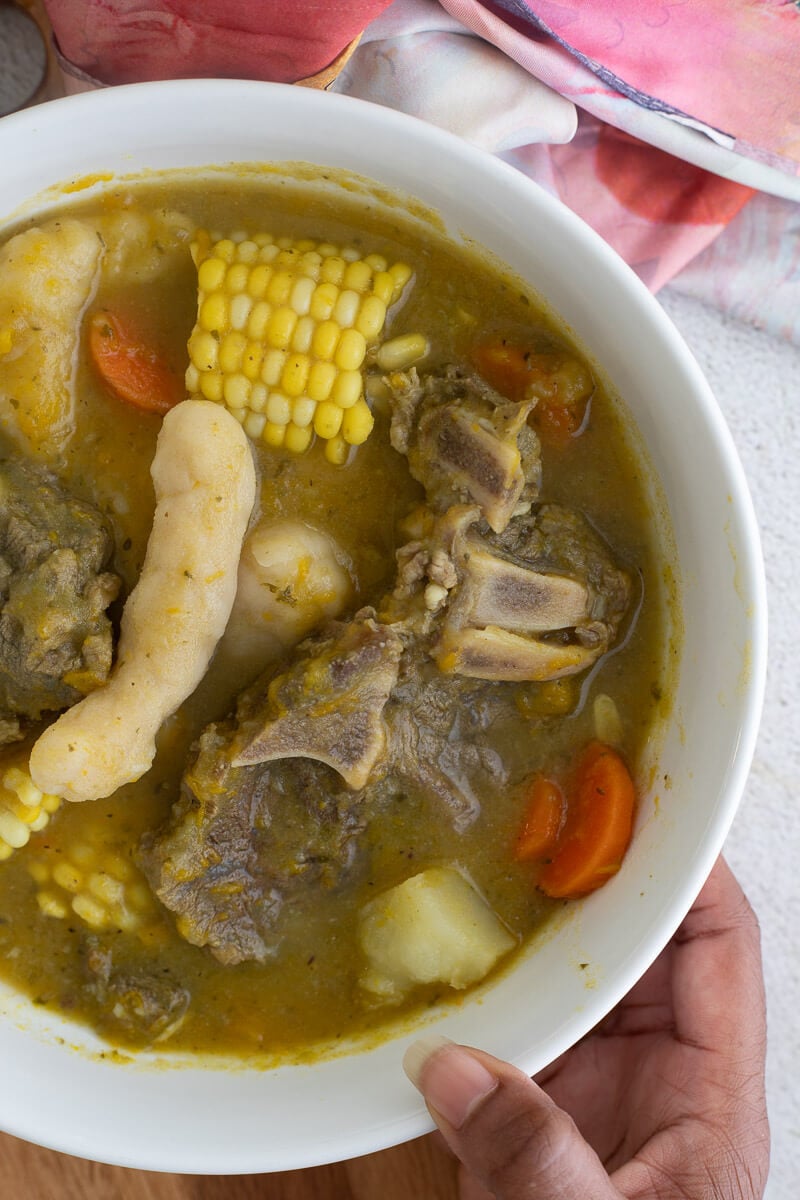 A serving of beef soup with vegetables and dumplings in a white bowl.