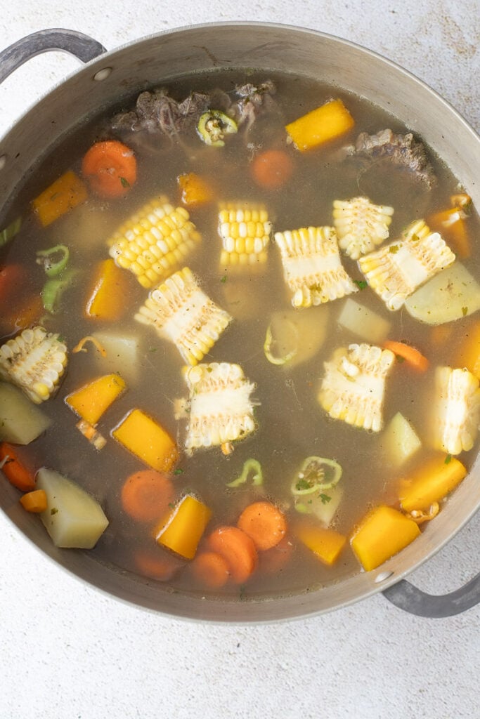 Ingredients to make Trini beef soup with pumpkin in a medium metal pot.