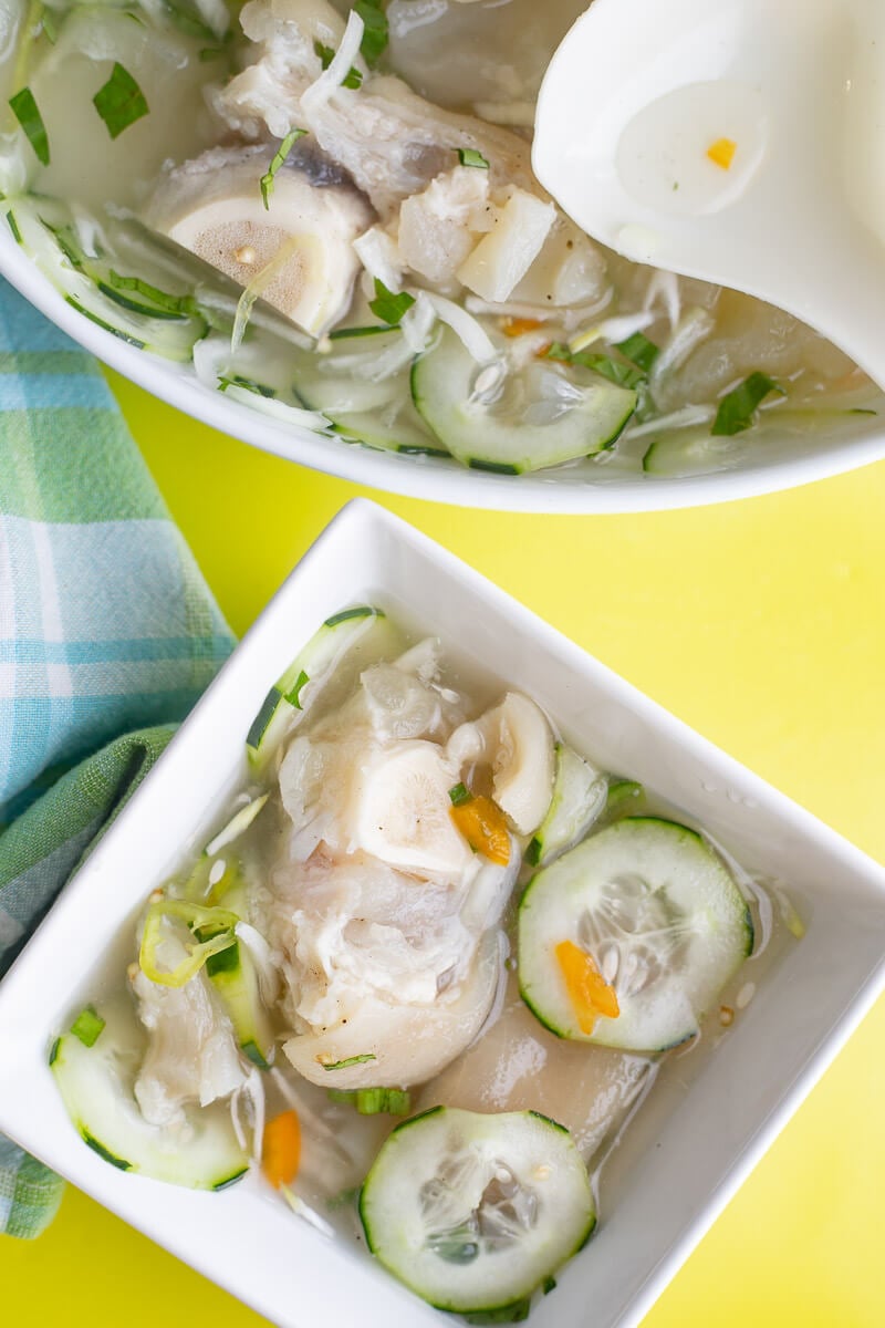 Souse in a large white bowl, with a serving in a small square bowl on a yellow background.