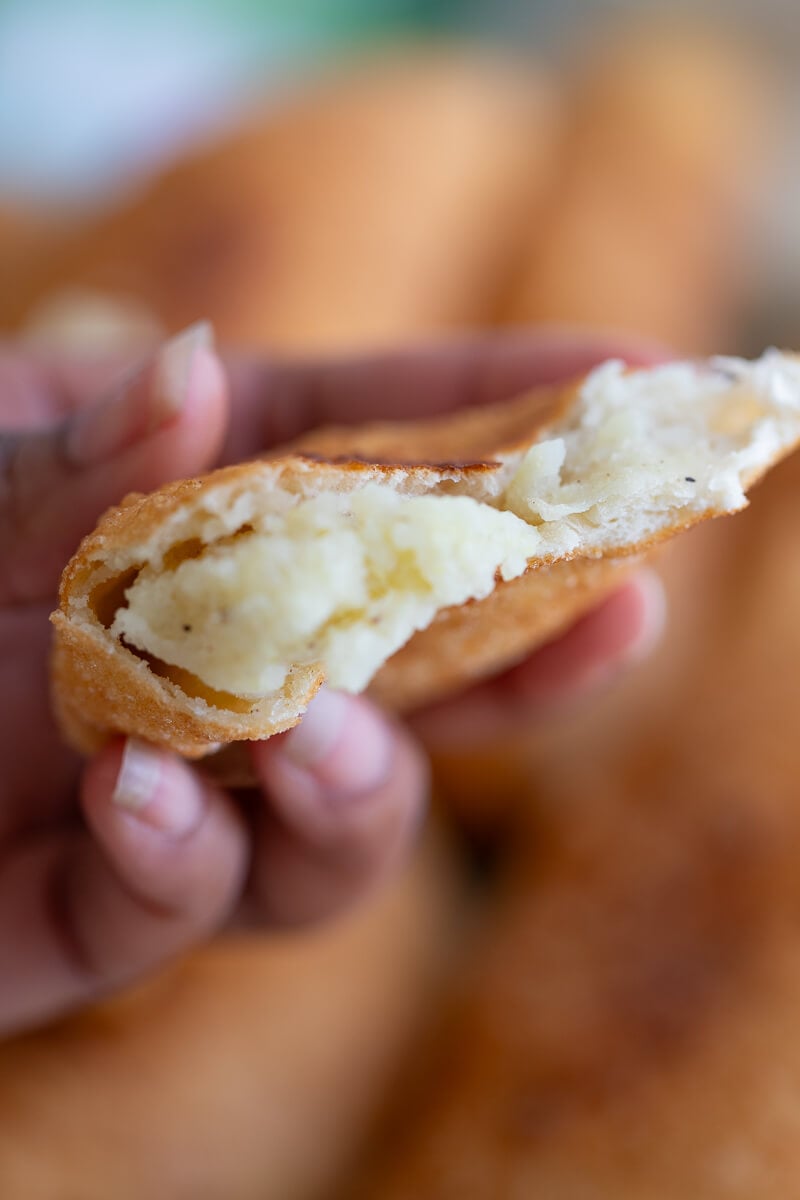 The inside seasoned potato filling for a trini aloo pie being held in hand.
