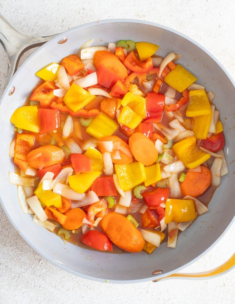 An overhead shot of the vegetables being cooked in the sauce pan and the addition of the ingredients to make the sauce.