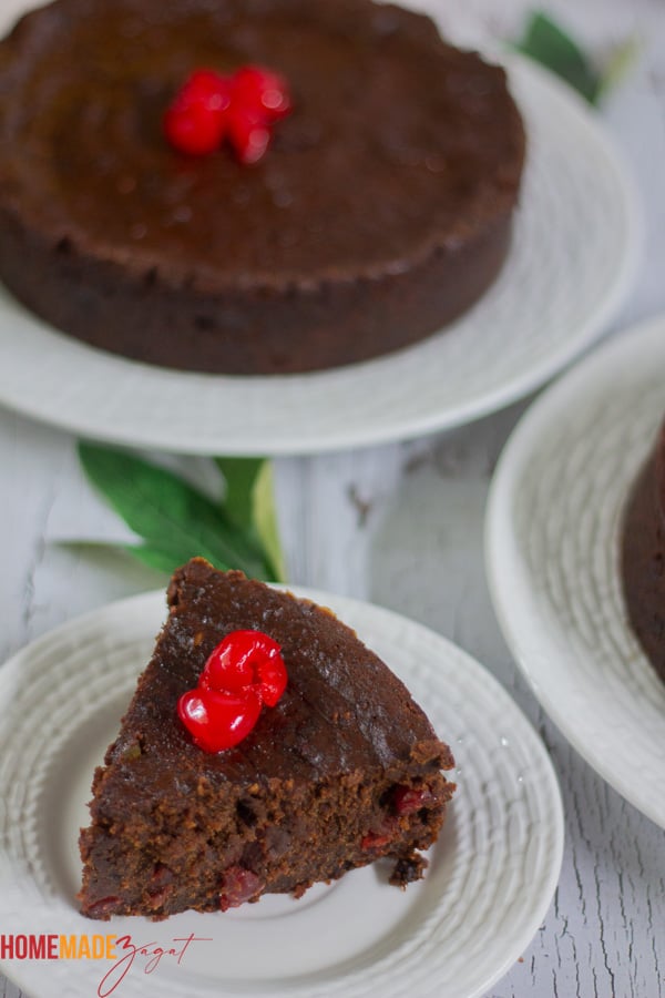 A slice of black cake with some cherries
