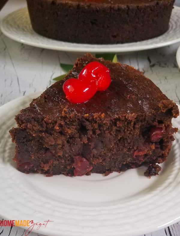 A slice of black cake on a white plate