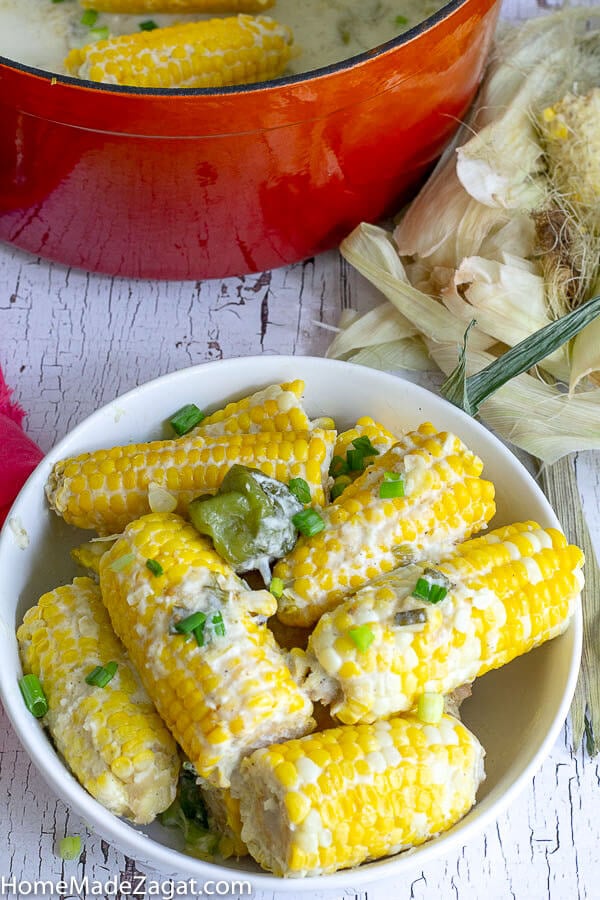 A big pot of finished boiled corn in a white bowl.