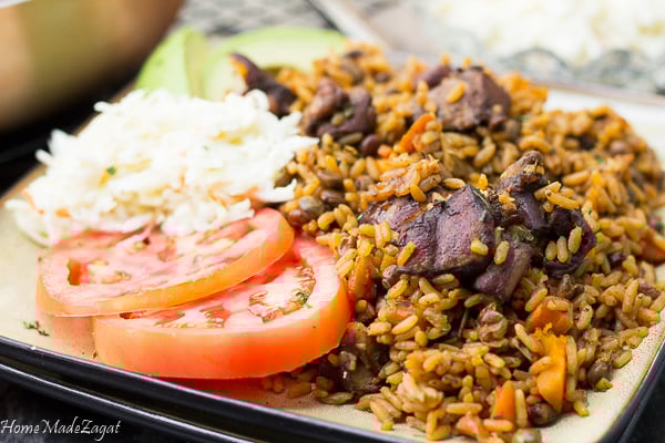 A full plate of pelau with sides of tomato slices.
