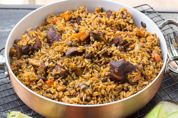 Close up of a finished pot of pelau with chicken, rice, peas and carrots.