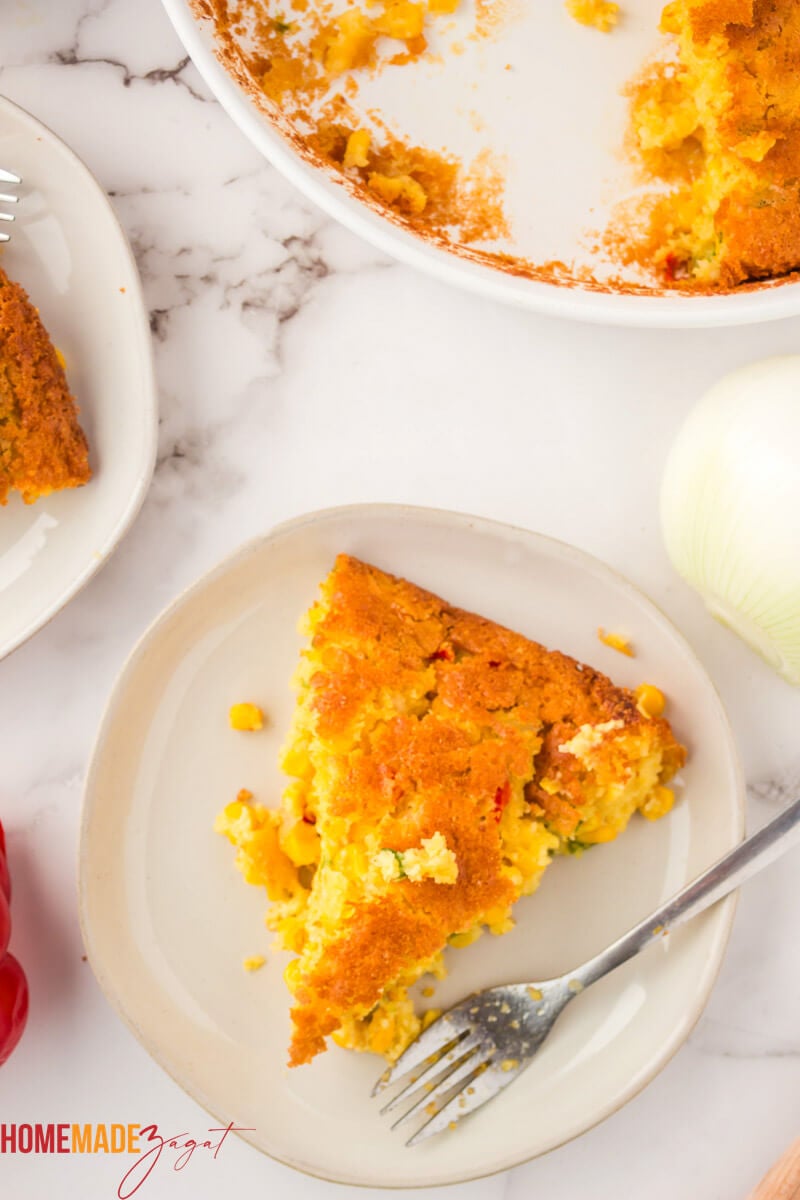 A close up of a slice of baked corn pie, on a white plate
